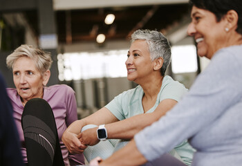 Fitness, health and group of senior women talking while resting after workout in the gym. Conversation, wellness and healthy elderly female friends speaking after exercise or training in sport center