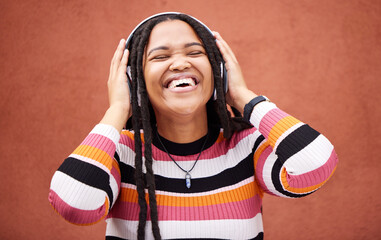 Black woman, music headphones and happy by wall in city for walk, adventure and me time with smile. Young gen z girl, audio streaming and excited listening on radio, website and happiness in metro