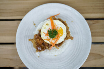 Spicy Chicken Rice garnished with egg and carrot pieces on a wooden table. Asian cuisine dishes for breakfast, dinner, or lunch.