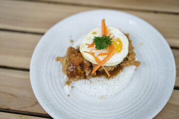 Spicy Chicken Rice garnished with egg and carrot pieces on a wooden table. Asian cuisine dishes for breakfast, dinner, or lunch.