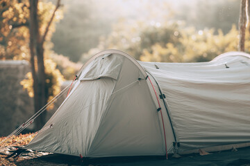 Gray tent on the grass in the forest The view behind is the mountain in the morning. Camping,...