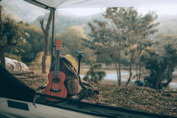 Camping equipment, bags, shoes, ukulele, tripod beside the tent in the morning. Object camp, Travel and vocation concept.