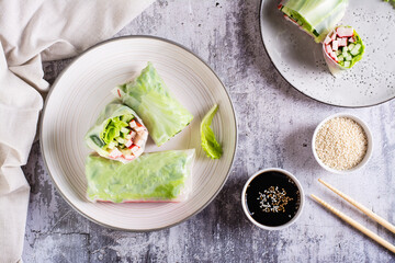 Vegetarian spring rolls with cucumber, crab sticks and lettuce on a plate on the table. Top view