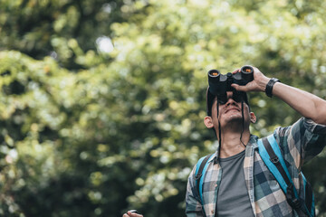 Hikers use binocular to see animals and view landscape  with backpacks in the forest. hiking and adventure concept.