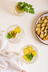 Cold pickleback cocktail with pickles and parsley in glasses on the table. Top and vertical view