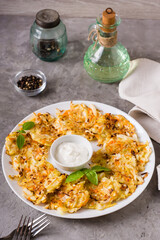 Cabbage and carrot fritters and sauce on a plate on the table. Vegetable food. Vertical view
