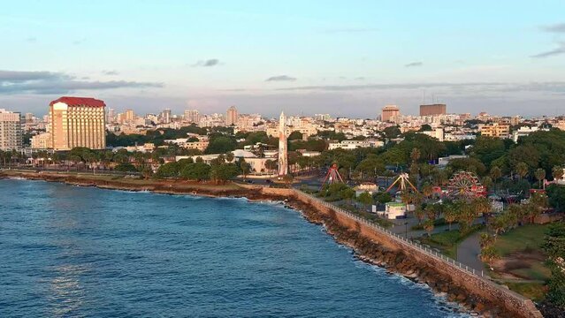 Obelisk in Juan Baron square and amusement park along Malecon at sunrise, Santo Domingo. Aerial forward and sky for copy space