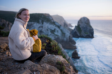 A woman sits on the Atlantic cliffs near Cape Roca, Portugal.