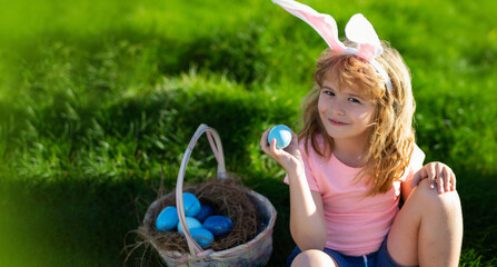 Child hunting easter eggs. Spring holidays. Cute kid in rabbit costume with bunny ears having easter. Horizontal photo banner for website header design with copy space for text.
