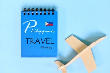 Philippines travel plan or itinerary written on blue notepad with flag and wooden airplane. Tour guide and outline.