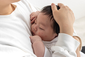 Fototapeta na wymiar 母親に抱っこされて寝る赤ちゃん（0歳2か月、日本人、男の子）