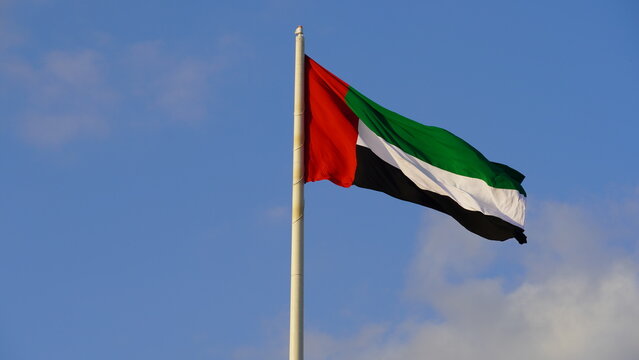 United Arab Emirates National flag waving in wind, Blue sky background