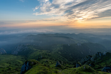 Panorama of green meadow with rocks and rocky mountains in romanian mountains in muntii ciucas with...
