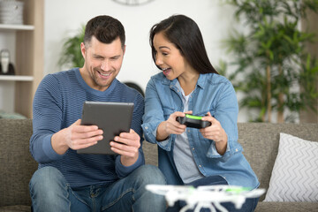 couple playing with a drone holding remote control and tablet