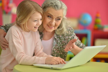 portrait of happy grandmother and daughter using laptop