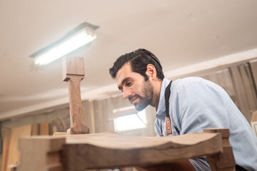 Professional craftsman working with furniture in wood workshop