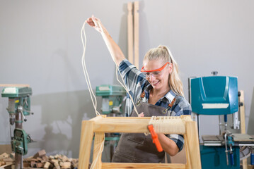 Young carpenter woman wearing glasses and working in wood workshop