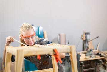 Young carpenter women wearing glasses and working in wood workshop