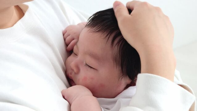 母親に抱っこされ、頭を撫でられて寝る赤ちゃん（0歳2か月、日本人、男の子）