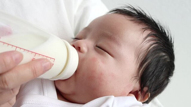 母親に抱っこされて寝ながらミルク飲む赤ちゃん（0歳2か月、日本人、男の子）