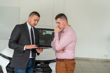  seller holding a clipboard tells the client all the details of the purchase of a new car