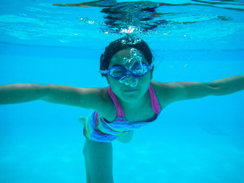 Young girl swimming under water in summer