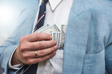 Businessman wear suit receive bribe and putting dollars money in pocket