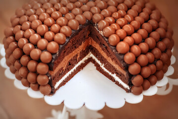 Chocolate birthday cake. Cake decorated with Maltesers chocolate balls. Chocolate cake on a stand. Chocolate cake with your own hands. Homemade chocolate cake. Cutaway cake.