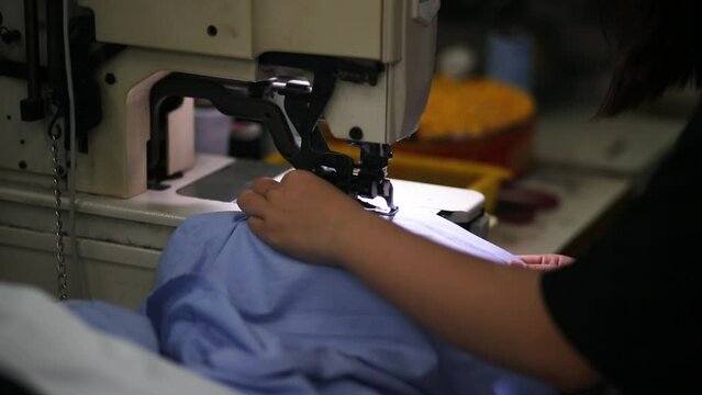 Close-up of worker using a sewing machine in factory; manufacturing industry