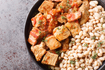White beans with fried pork Freginat close-up in a plate on the table. Horizontal top view from above