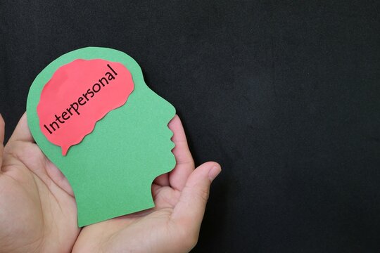 Interpersonal intelligence in psychology concept. Hand holding human head profile with word text on brain.	