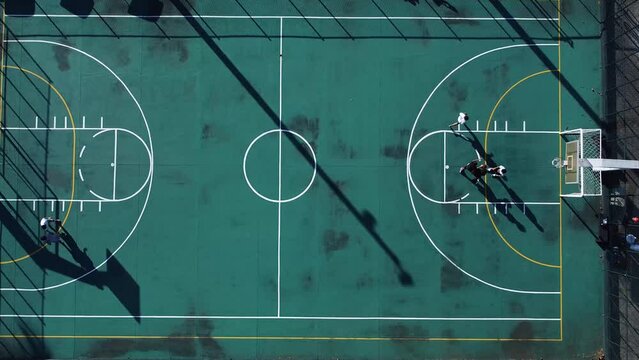 vista superior drone alejandose sobre una cancha de baloncesto mientras la gente juega, UHD, puesta de sol de v&iacute;deo.