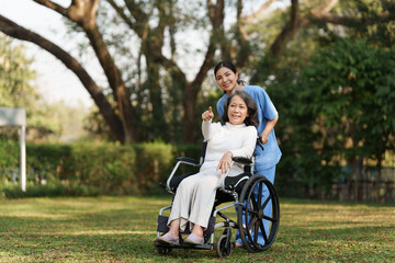 Elderly asian senior woman on wheelchair with nurse. Nursing home hospital garden concept