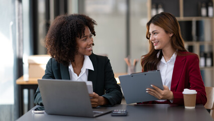 African American businesswoman and Asian businesswoman working together as a team to get their project done.
