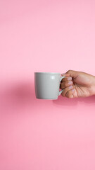 Male human hand holding glass of liquid drinking water. on a pink background