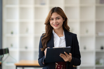 Portrait of young charming businesswoman working and holding paper document in her hands while working for the meeting.