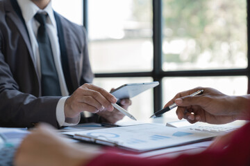 Group of Asian business people meeting new startup project pointing discussion graph and data analysis charts and graphs business finance inside office accounting concept management renew.