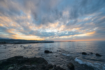 Dynamic fast moving clouds and red sunset. rocky coast. The view of the sea at dusk. Shimen District, New Taipei City, Taiwan