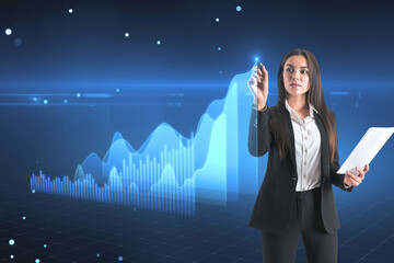Market analyzing and economy growth concept with young businesswoman with stylus on virtual touch screen with rising digital financial chart graphs and diagram on abstract blue background