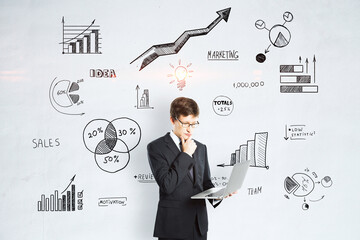 Investing, analysis and brainstorming concept with businessman using modern laptop on light wall...