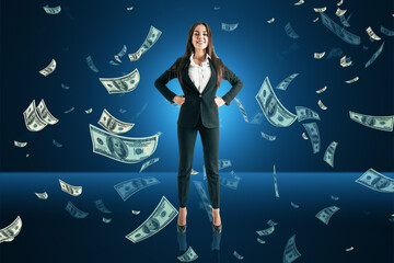 Happy young european business woman with falling dollar bills on blue background. Success, lottery win and money concept.