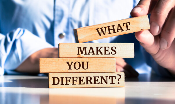 Close up on businessman holding a wooden block with "What Makes You Different?" message