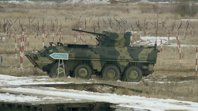 Armored personnel carrier at the training ground performs exercises to pass obstacles. Armored personnel carriers (APC) are driving on the road. Armored wheeled vehicles on exercises in Ukraine.