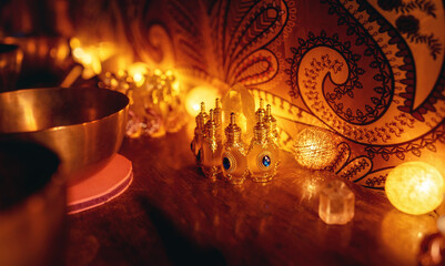 A closeup of perfumes bottles in candlelight and tibetan bowls.