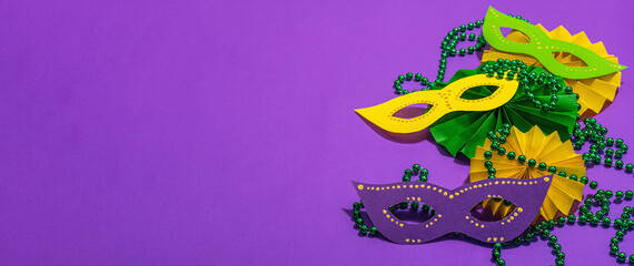 Festive Mardi Gras masquerade purple background. Fat Tuesday carnival, masks, beads, traditional decor