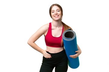 Young sport woman going to yoga classes while holding a mat over isolated chroma key background posing with arms at hip and smiling