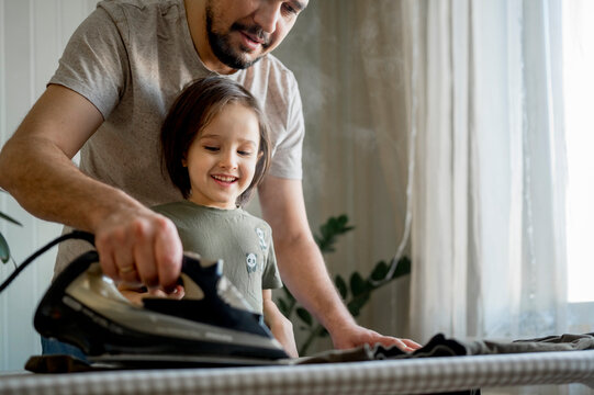 Father and son ironing clothes at home