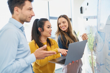 Businesswoman with laptop in brainstorming session with colleagues at office