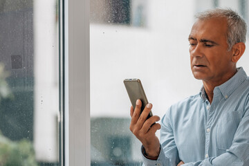 adult man with phone at window