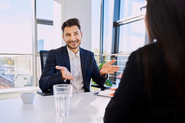 Happy businessman gesturing in meeting with colleague at office